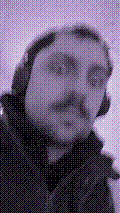 a selfie of a white person, wearing either headphones or a helmet, making an odd expression. the photo is edited to be colorized into a monochrome purple-ish color palette.